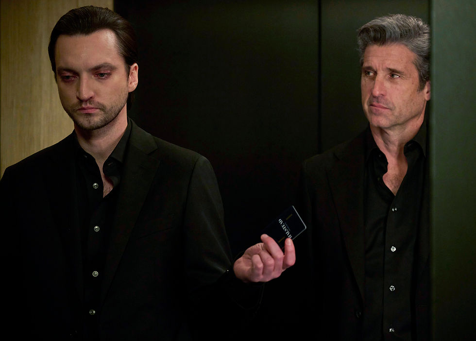 Two men in black suits stand in an elevator. One holds a business card. The mood is tense. Background is dark with wood paneling.
