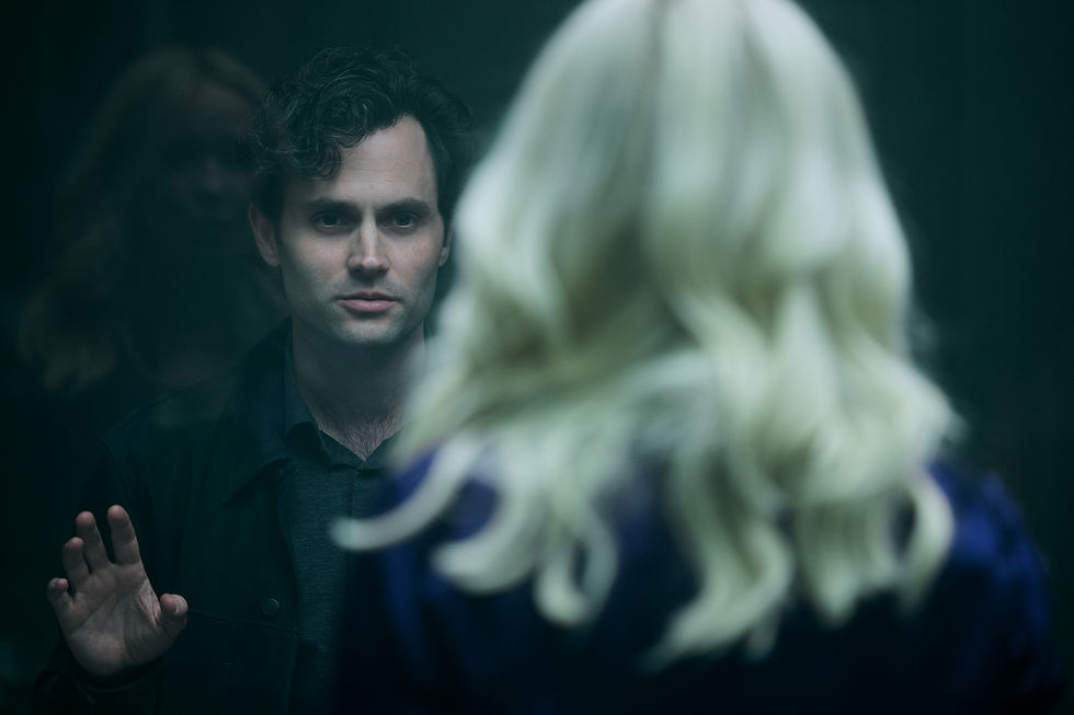 Man in a dark jacket faces a woman with blonde hair in a reflective surface, hand raised, appearing tense. Dimly lit background.