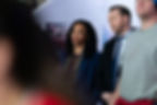 Two people stand indoors, both appearing serious. A poster with "Future" is in the background. The scene has a somber mood.