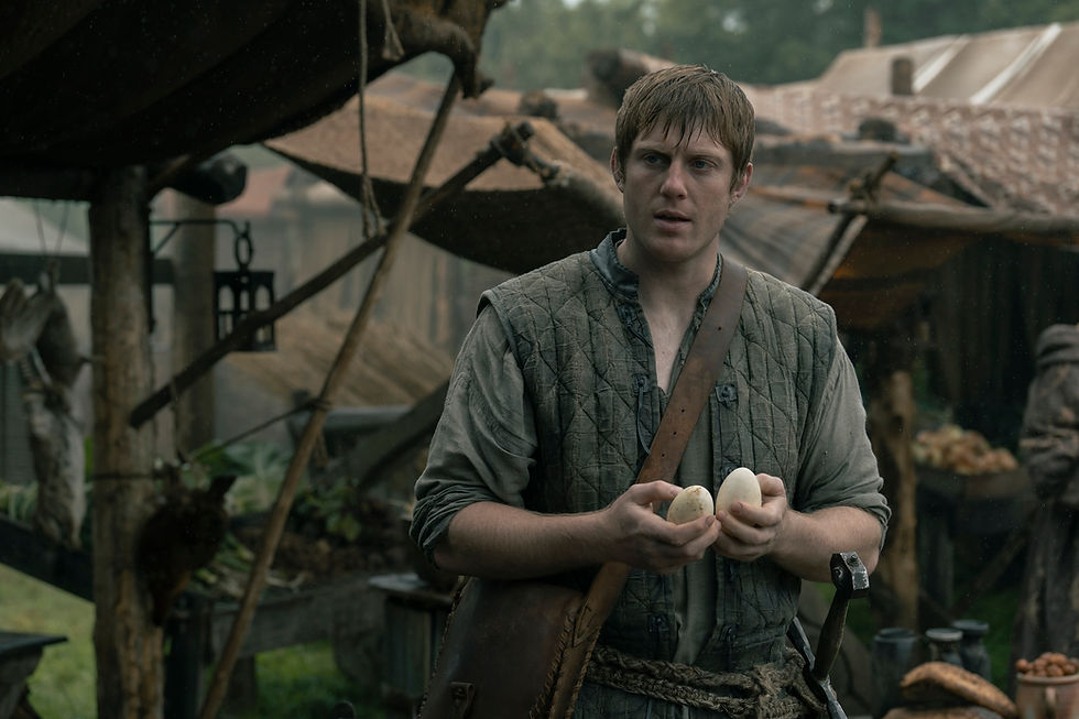 A man holds two eggs in a rustic outdoor market, wearing a quilted vest. Background includes wooden structures and hanging items. Mood is thoughtful.