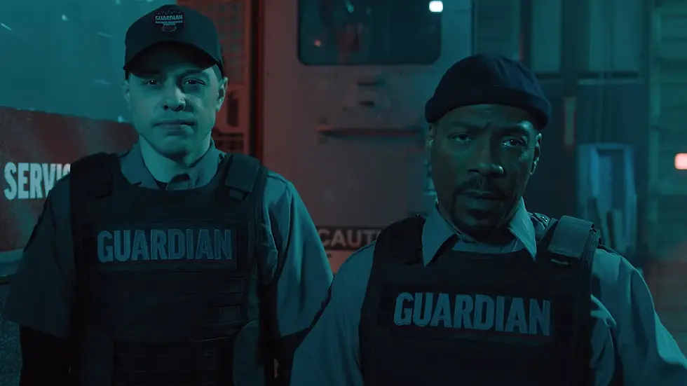 Two security guards in "Guardian" vests stand seriously in a dimly lit room with industrial background, blue-green lighting.