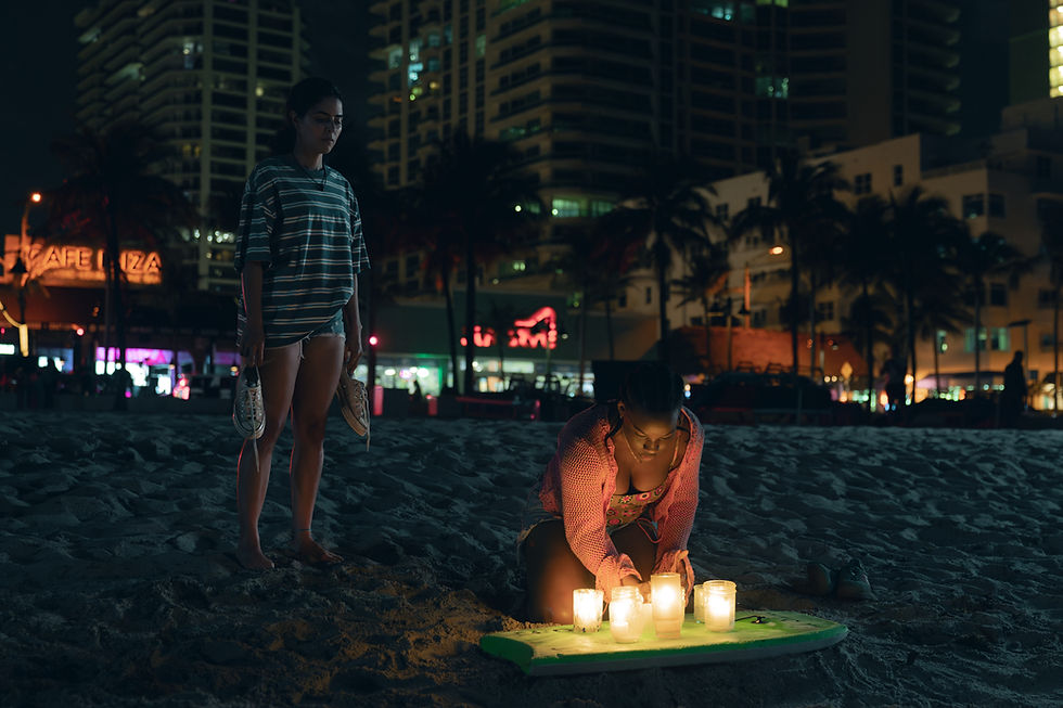 women on beach, one lighting a candle