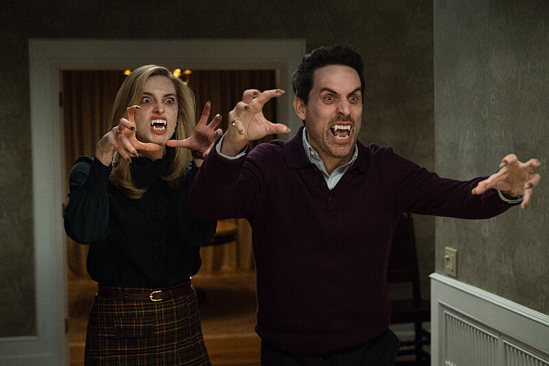 Angry couple in a dim hallway, snarling and clawing at the air, with a doorway and wood-paneled room behind them.