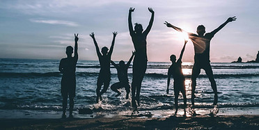 Joyful people jumping on a beach at sunset