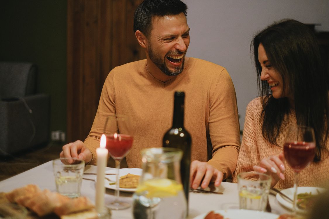 Couple laughing together over dinner, representing renewed connection and affection