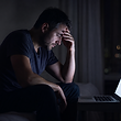 a man viewing a laptop in the dark