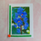 Thumbnail: Handmade greeting card featuring a close-up photograph of vibrant blue Lupine flowers with orange-yellow centers, bordered wi
