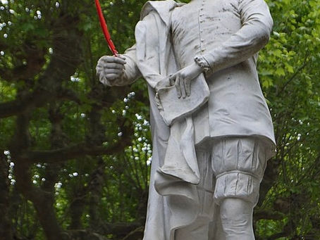 une statue d'un jeune homme tout en blanc portant une plume rouge