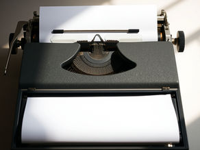 Machine à écrire noire avec une feuille de papier vierge, éclairée par un faisceau de lumière. Ambiance vintage et classique.