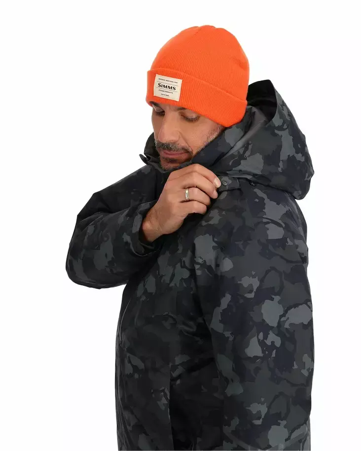 Homme portant la veste Simms Challenger camouflage et tuque orange