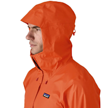 Profil d'un homme portant la veste Patagonia Torrentshell 3L orange avec capuche.