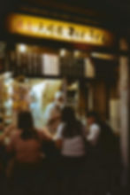 A bustling, small soba shop at night with counter seating.