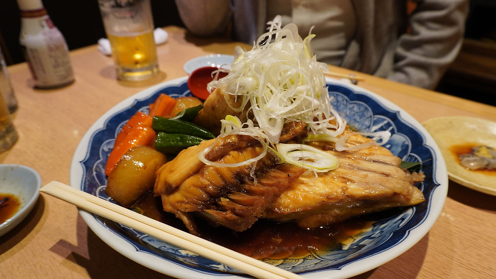 Plate of marinated fish with vegetables topped with green onion and chopsticks across it