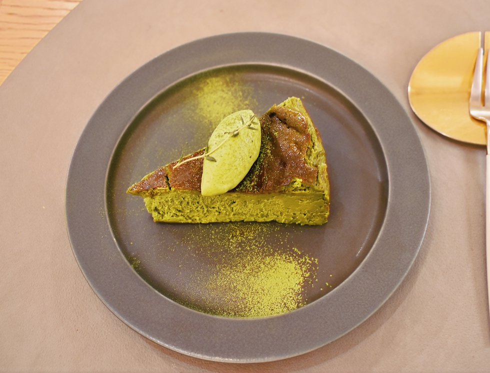 Matcha basque cheesecake on a greay plate topped with powdered matcha.