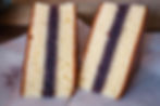Two slices of Siberia cake with red bean filling on white paper, set against a blurred brown background. Light and fluffy texture.
