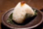 Onigiri with a topping of braised pork on a black plate.