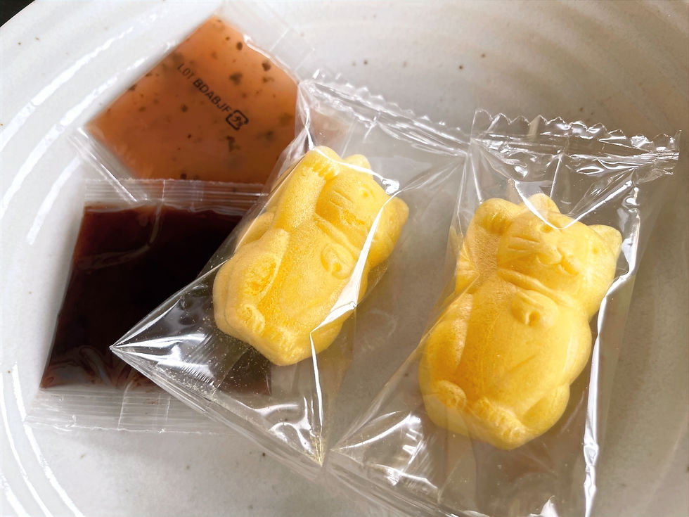 the manekineko monaka on a white plate before assembly. two halves of the monaka and two packs of anko (sweet red bean paste) are individually wrapped.