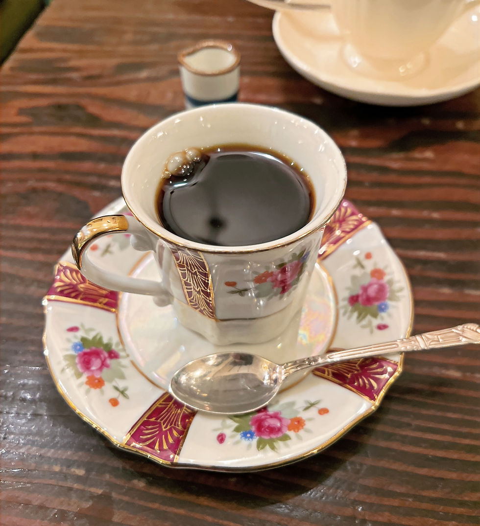An ornate cup of coffee holding black coffee at a kissaten.
