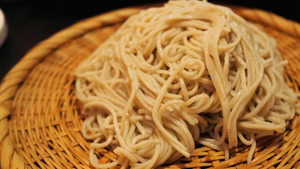 A close-up of freshly cooked soba noodles piled on a woven bamboo mat against a dark background.
