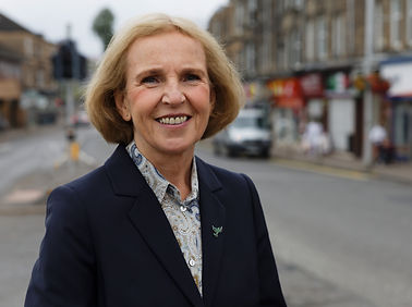 Susan in a black blazer standing in front of the high street in Bishopbriggs