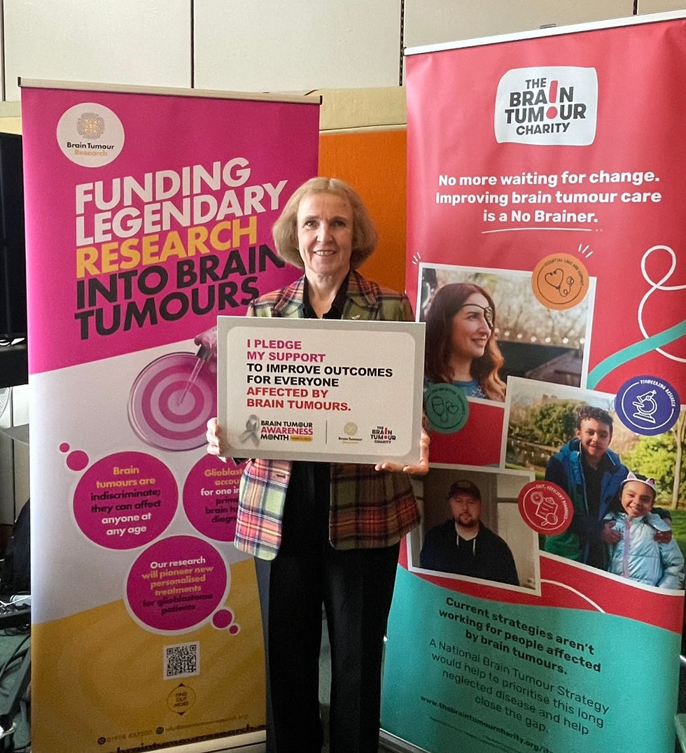 Susan holds 'Outstanding Recognition' award, 'Brain Tumour Charity' research banners.