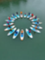 Group circle during a SUP coaching session on calm water.