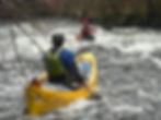 Paddlers in an open canoe coaching session on white water.