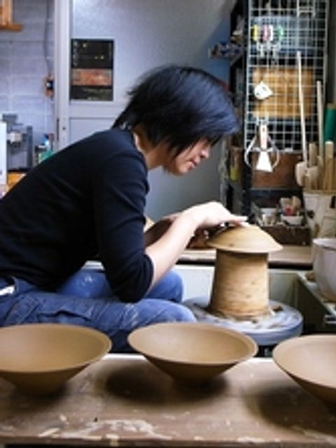 ろくろの前で作業する作家と、手前の台に並ぶ成形した鉢