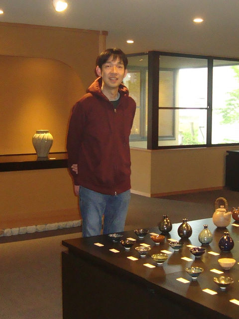 会場に立つ作家の木村宜正さん。手前の台に小さな器が並ぶ