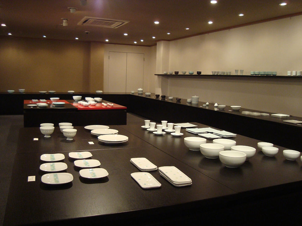 白磁の鉢・皿・角皿が広い展示台に並ぶ、谷口左和子陶展の会場全景