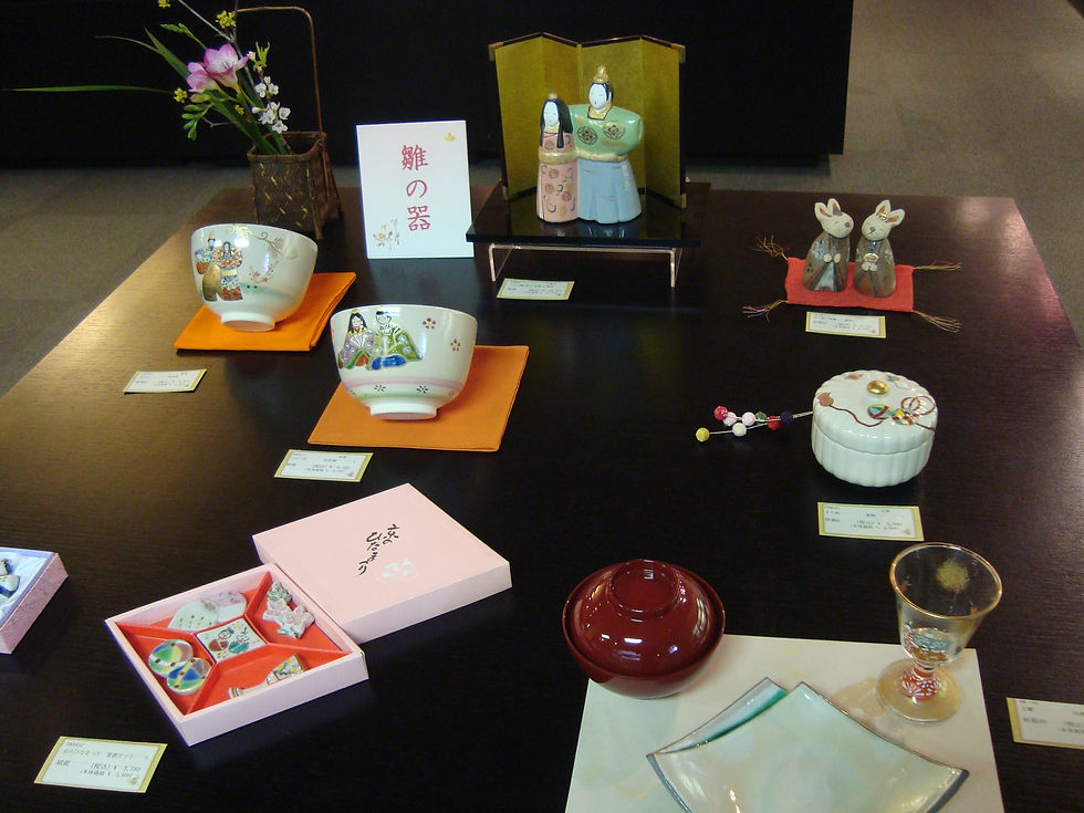 「雛の器」の札とお雛さま、雛柄の抹茶碗や小箱を並べた展示台