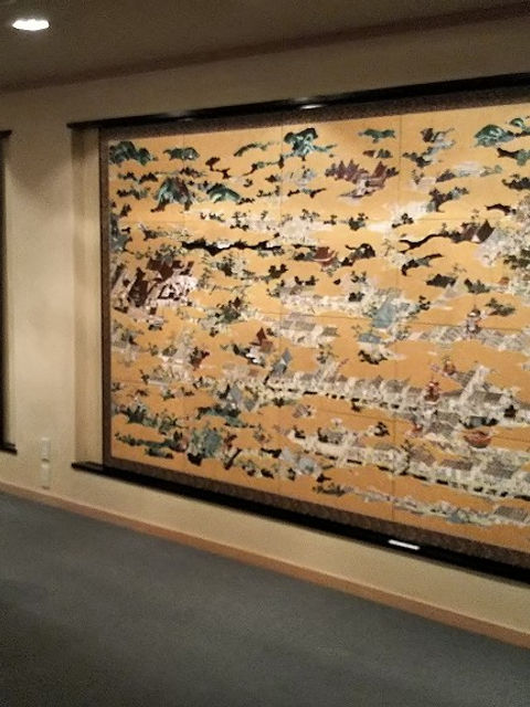 洛中洛外図の陶板が壁一面に並ぶ展示スペース。手前にソファ