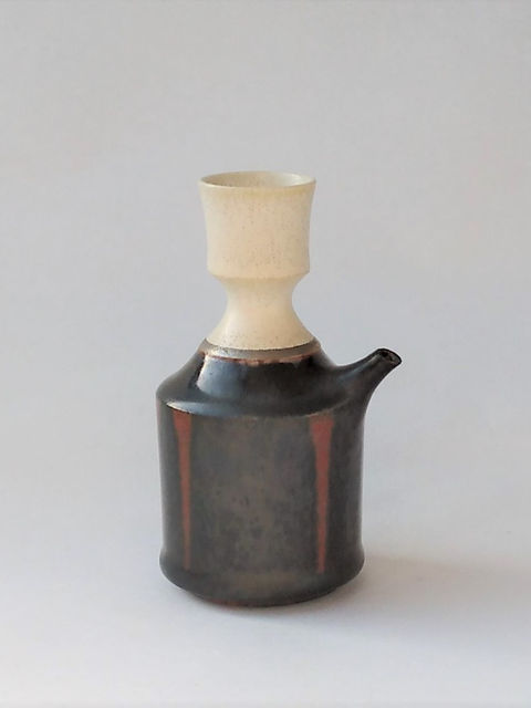 白い口づくりと黒褐色の胴に朱の縦縞が入った片口の酒器