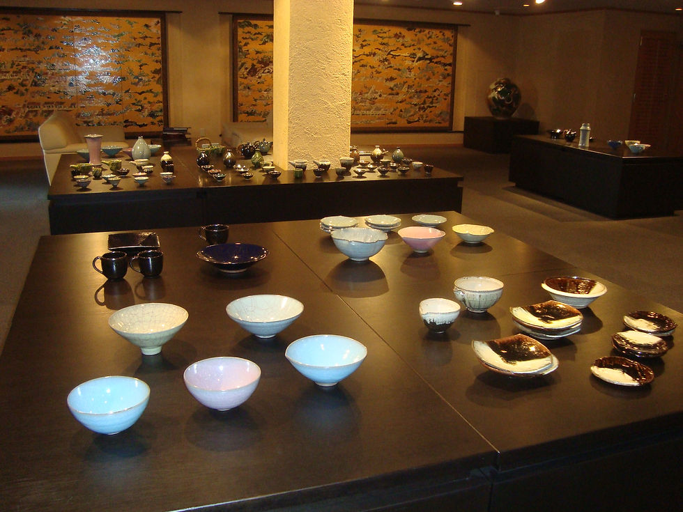 黒い台に淡い青や白の茶碗と黒釉の皿を並べた木村陶展の会場