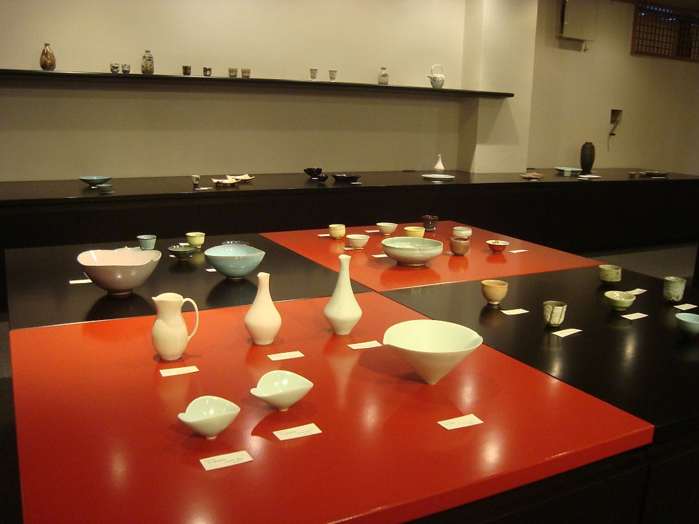 赤い展示台と黒い展示台に、白磁の花入やピッチャー、小鉢を並べた酒器展前の展示室