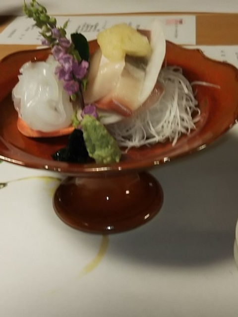 朱塗りの高台の器に盛ったお造り。紫の花を添え、醤油の小皿が手前に見える