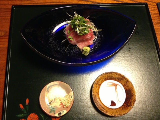 紺色のガラスの鉢に、ネギを添えたマグロを盛り、塩と醤油の小皿を添えた一品(いふき)