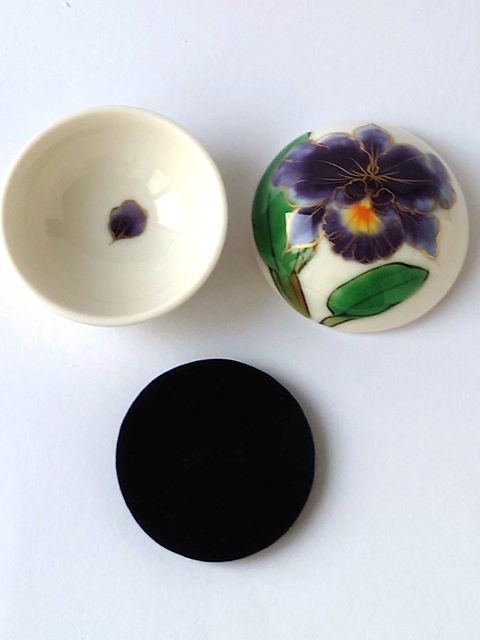 紫の花が描かれた陶器の美しいリングケースと黒いクッション