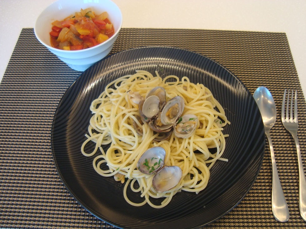 黒い皿に盛ったあさりのパスタと、トマトの小鉢
