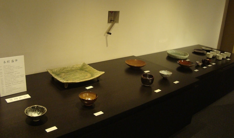 盛伸さんの作品が並ぶ展示台と壁の解説パネル