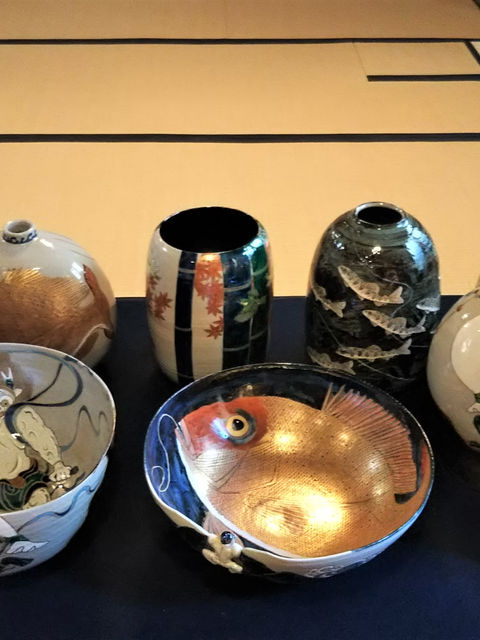 山本雄次さんの作品を畳に並べた展示。鬼や鯛を描いた鉢と花瓶、壺