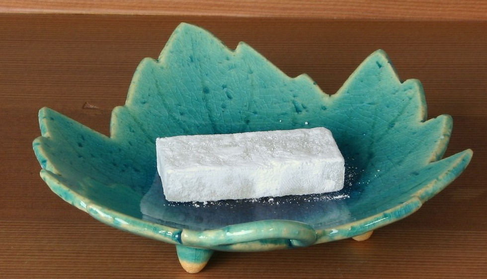 緑のぶどうの葉形の皿に、白い涼菓を一切れのせたところ