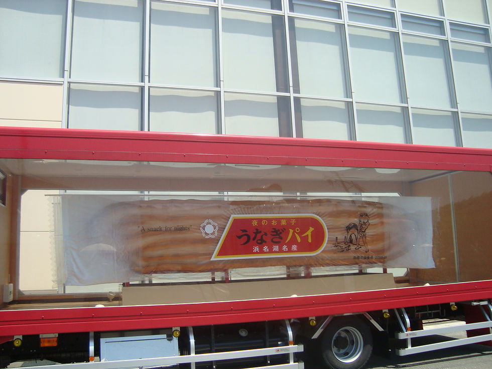 赤い大型トラックの荷台に飾られた、大きな「うなぎパイ」の形のオブジェ