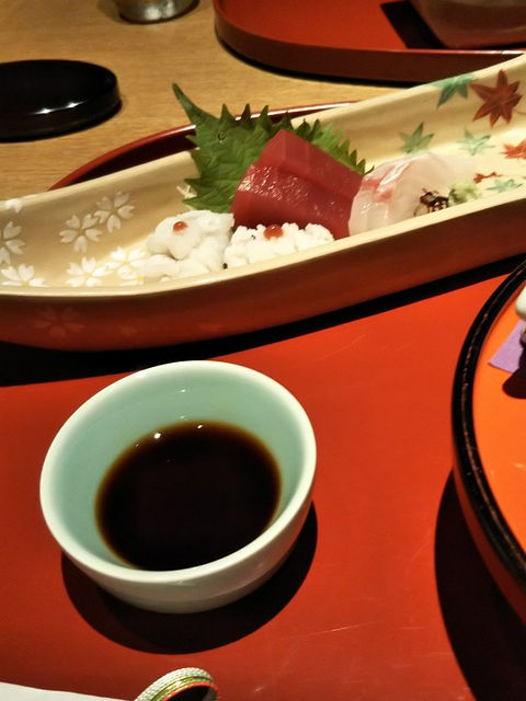 刺身の長皿と醤油を入れた青磁の小鉢。赤い漆の卓