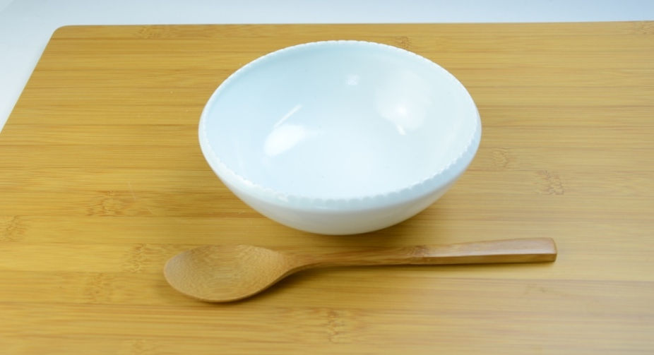 木のスプーンを添えた、縁がぎざぎざの白磁の楕円鉢