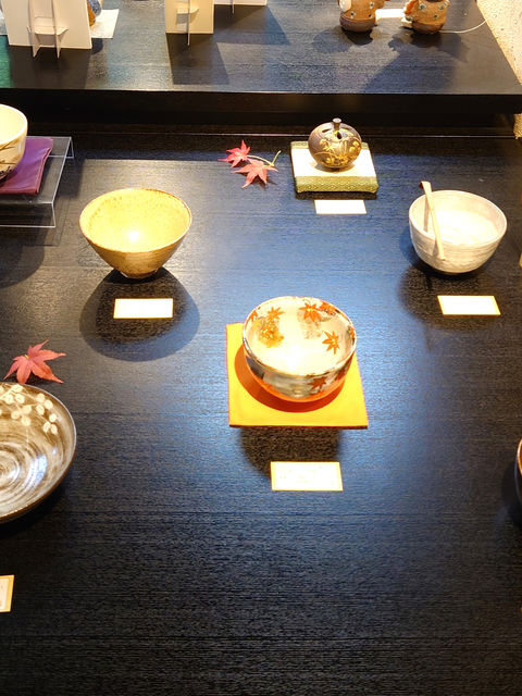 黒いテーブルに展示された紅葉柄の抹茶茶碗と茶道具