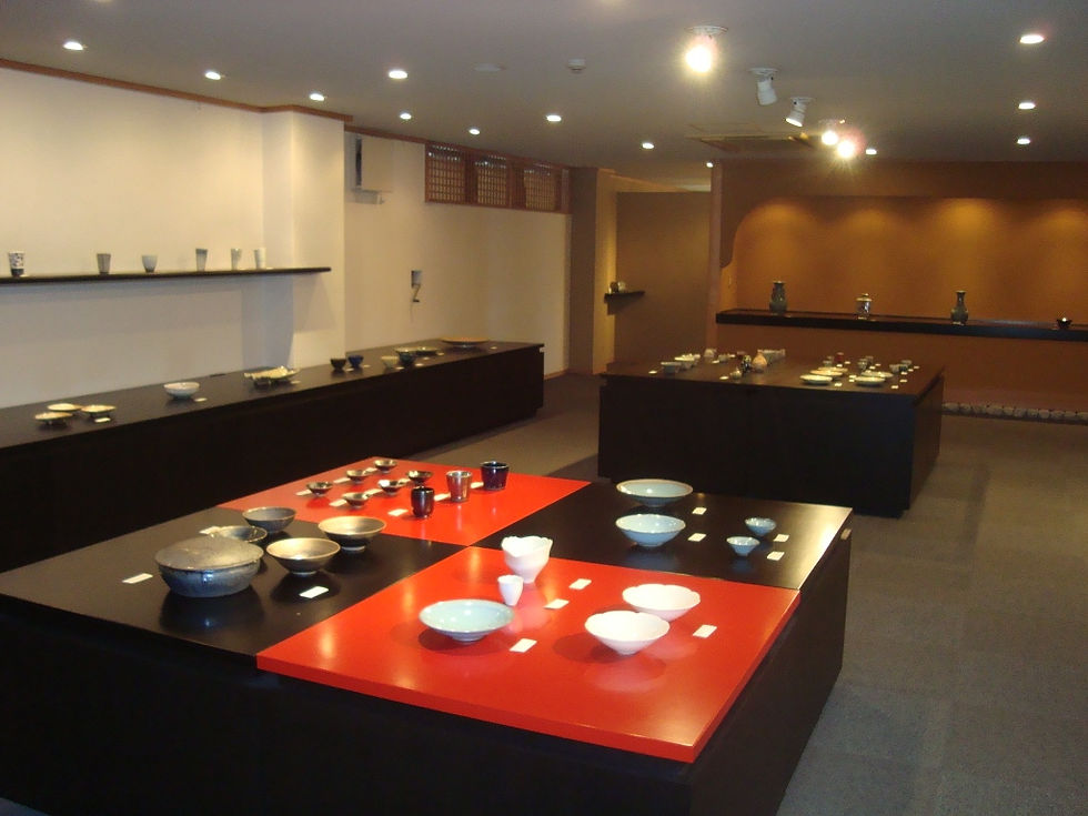赤い漆の台に白い鉢や茶碗が並ぶ二階ショールームの全景