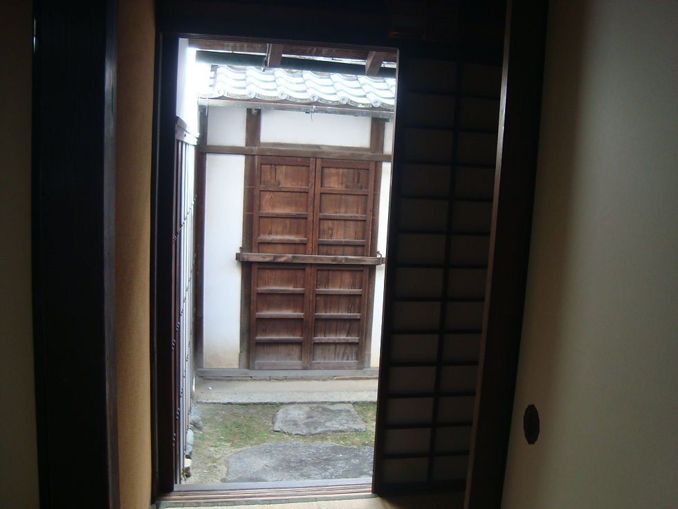 髙木家の建物の戸口から見える土蔵の扉と庭