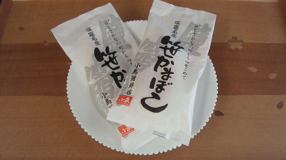 縁飾りのある白い皿に乗せた、「笹かまぼこ」の包み二つ