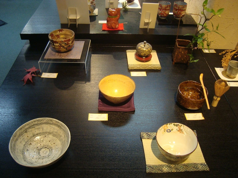 茶盌や香合、茶筅を紅葉とともに並べた秋の展示台